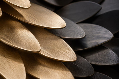 Champagne gold bronze wall sculpture Torrente, a continuous ribbon folded into running waves, on a plaster wall.