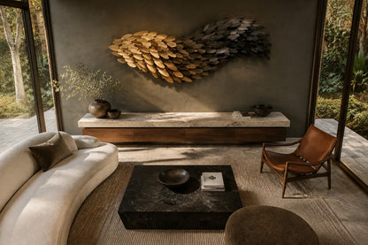 Champagne gold bronze wall sculpture Torrente, a continuous ribbon folded into running waves, on a plaster wall.