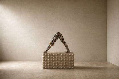 Bronze strut-cage sculpture Sbalzo forming an inverted arch, gilt and blackened, on a beaded travertine block.