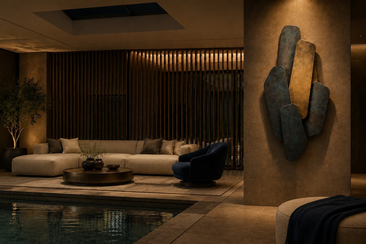 Shazaya 140 — 140 cm wall sculpture of overlapping rounded slabs in blue patinated bronze and brass, the same room at night, lamps on