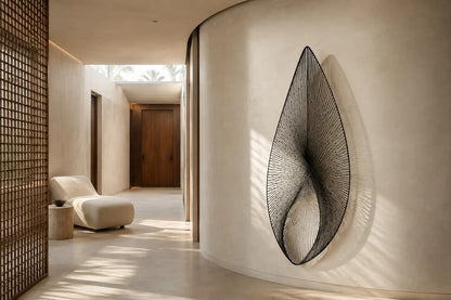 Satin steel steel wall sculpture Punta, a tapered leaf blade on a concealed bracket, on a plaster wall.