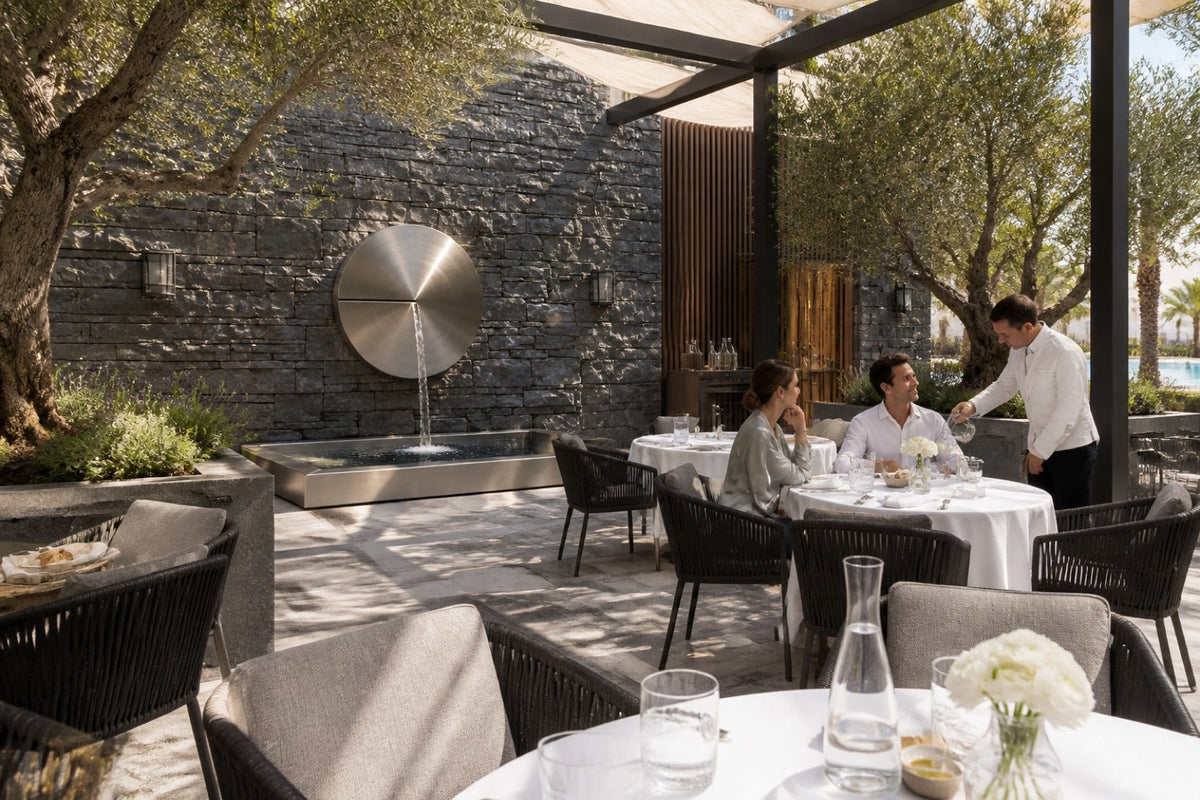 Solace — Ø 100 cm brushed stainless disc wall fountain, installed on the wall in a furnished setting