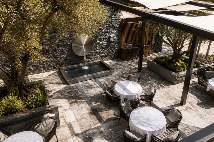 Solace — Ø 100 cm brushed stainless disc wall fountain, seen from above in the setting