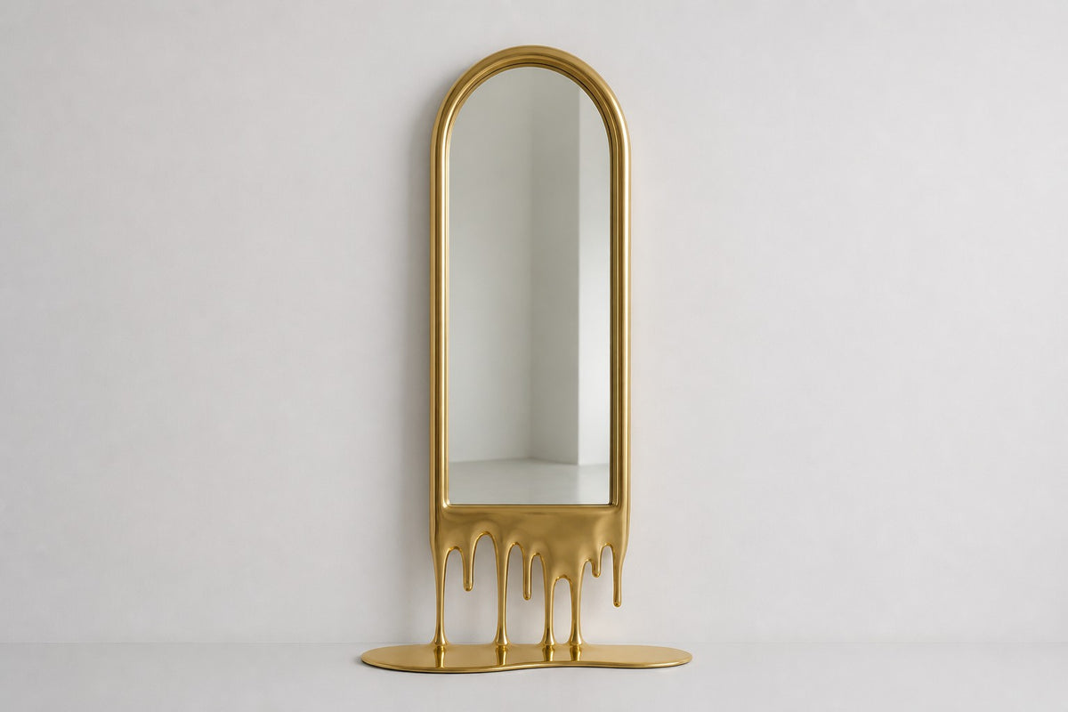 Stilla — tall arched floor mirror whose champagne brass frame melts into drips, studio front view