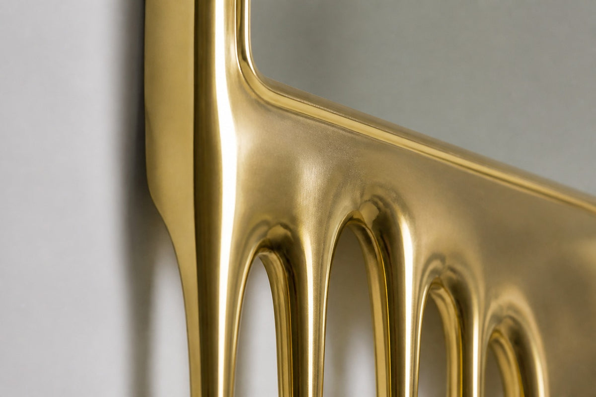 Stilla — tall arched floor mirror whose champagne brass frame melts into drips, close detail of the surface and edge
