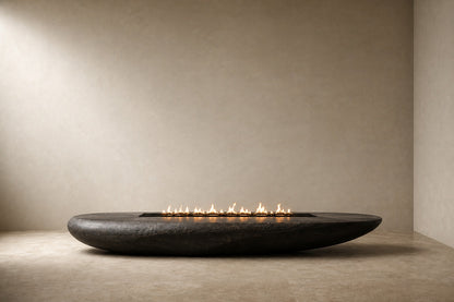 Charcoal-bronze stone fire table Suiran 220, charcoal with a warm bronze cast, on a pale stone floor.
