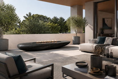 Charcoal-bronze stone fire table Suiran 220, charcoal with a warm bronze cast, on a pale stone floor.