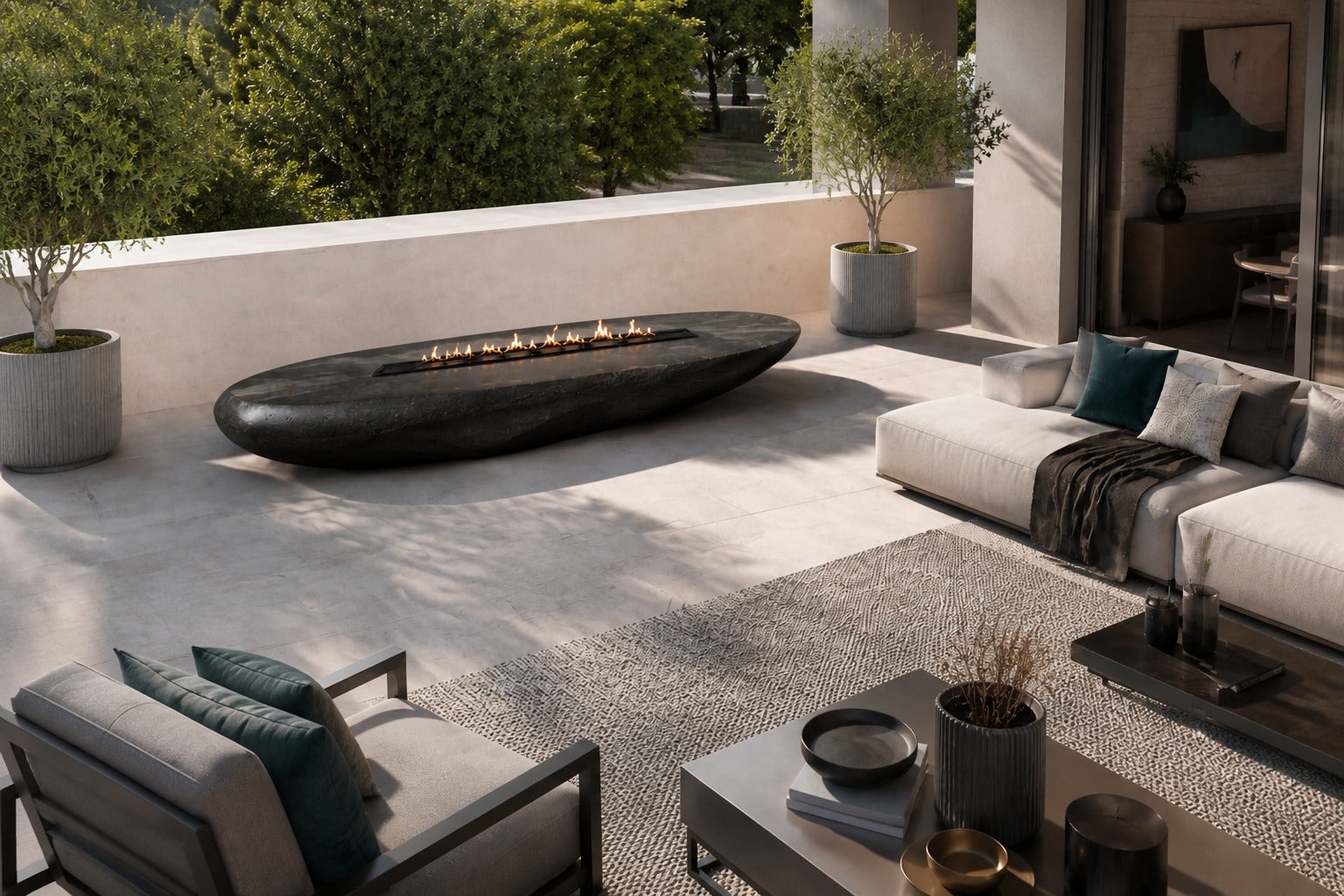 Charcoal-bronze stone fire table Suiran 220, charcoal with a warm bronze cast, on a pale stone floor.