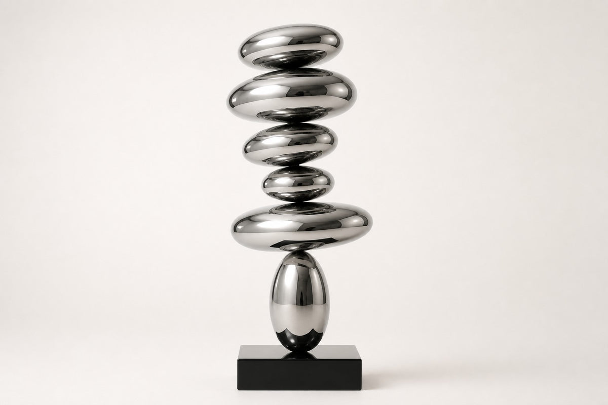 Suiseki — mirror chrome stacked pebble sculpture on a black base, studio front view