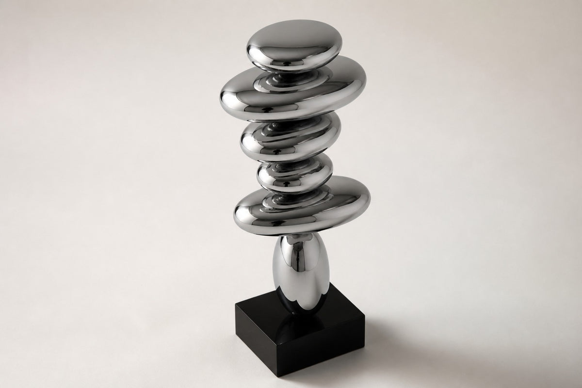 Suiseki — mirror chrome stacked pebble sculpture on a black base, studio side angle showing its depth