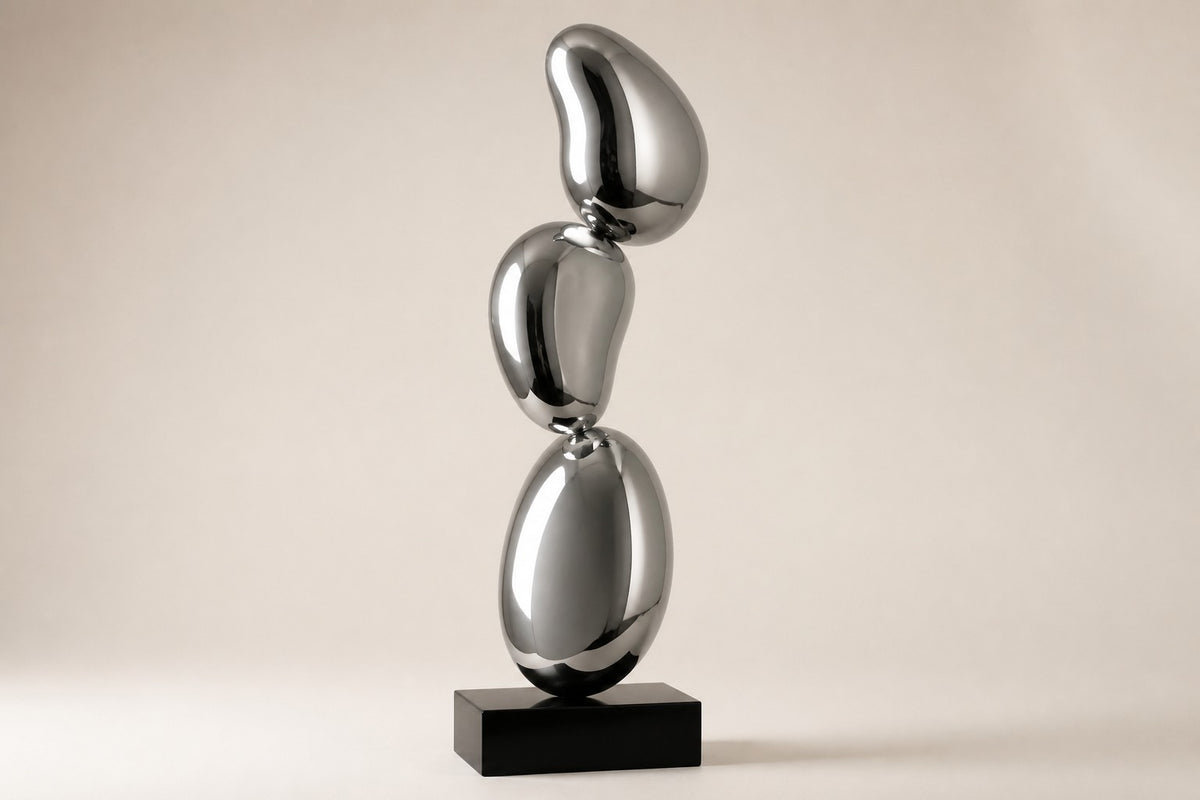 Tamago — mirror chrome stacked ovoid sculpture on a black base, studio side angle showing its depth