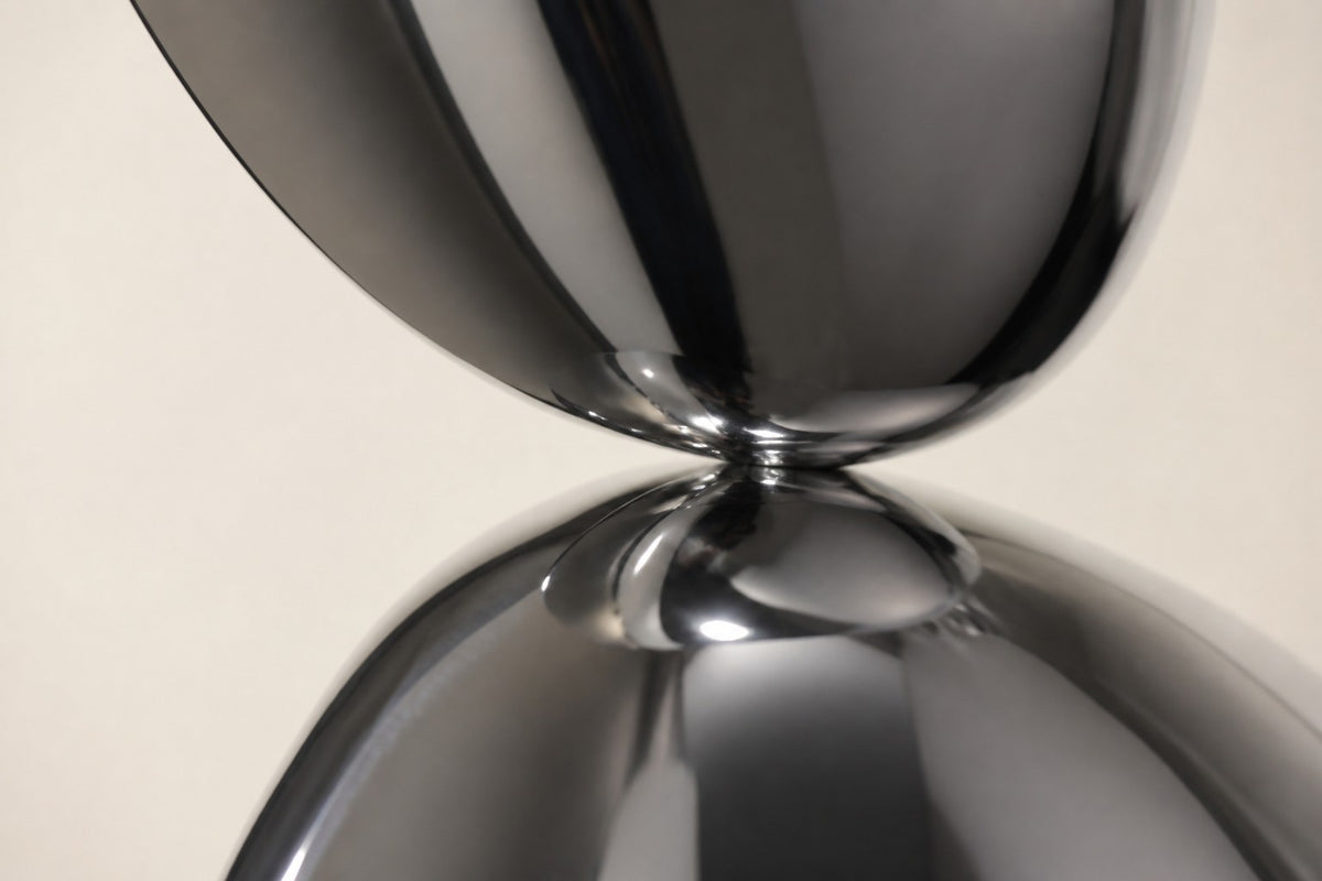 Tamago — mirror chrome stacked ovoid sculpture on a black base, close detail of the surface and edge