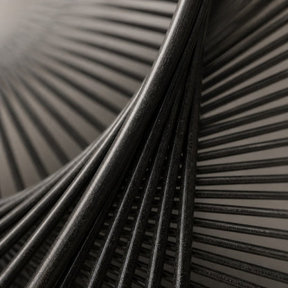 Charcoal steel wall sculpture Gemelos, two matched voids drawn in fine wire across one rim, on a plaster wall.