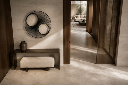 Charcoal steel wall sculpture Gemelos, two matched voids drawn in fine wire across one rim, on a plaster wall.
