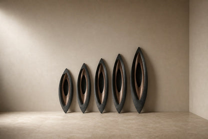 Five graduated lens-shaped bronze forms in ascending order, leaning against a plaster wall.