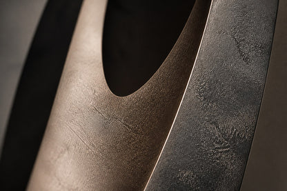 Five graduated lens-shaped bronze forms in ascending order, leaning against a plaster wall.