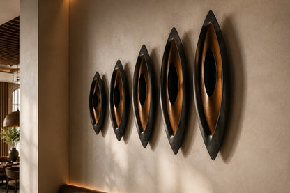 Five graduated lens-shaped bronze forms in ascending order, leaning against a plaster wall.