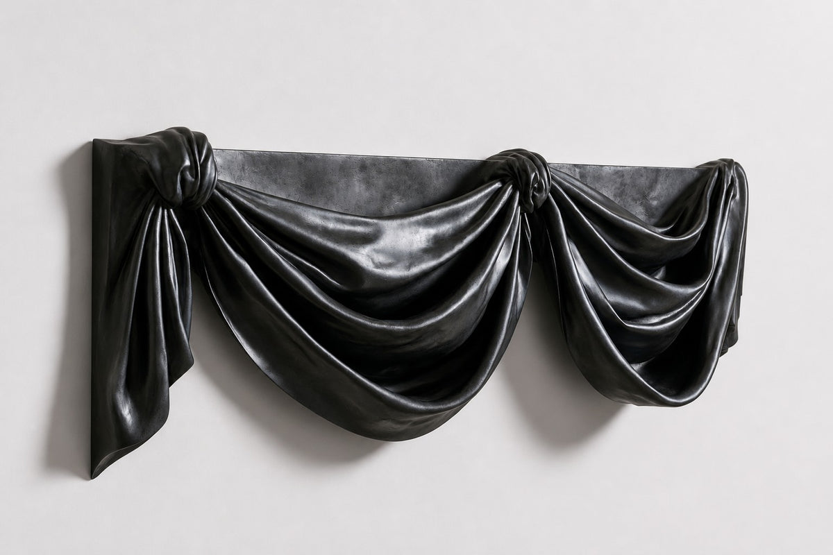 Telón — black bronze wall sculpture of theatre drapery in two deep swags, studio side angle showing its depth