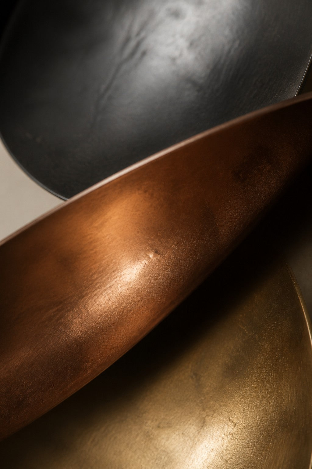 Terzetto — 90 × 150 cm wall sculpture of three stacked bowls in black, copper and gold, close studio detail of the surface and material