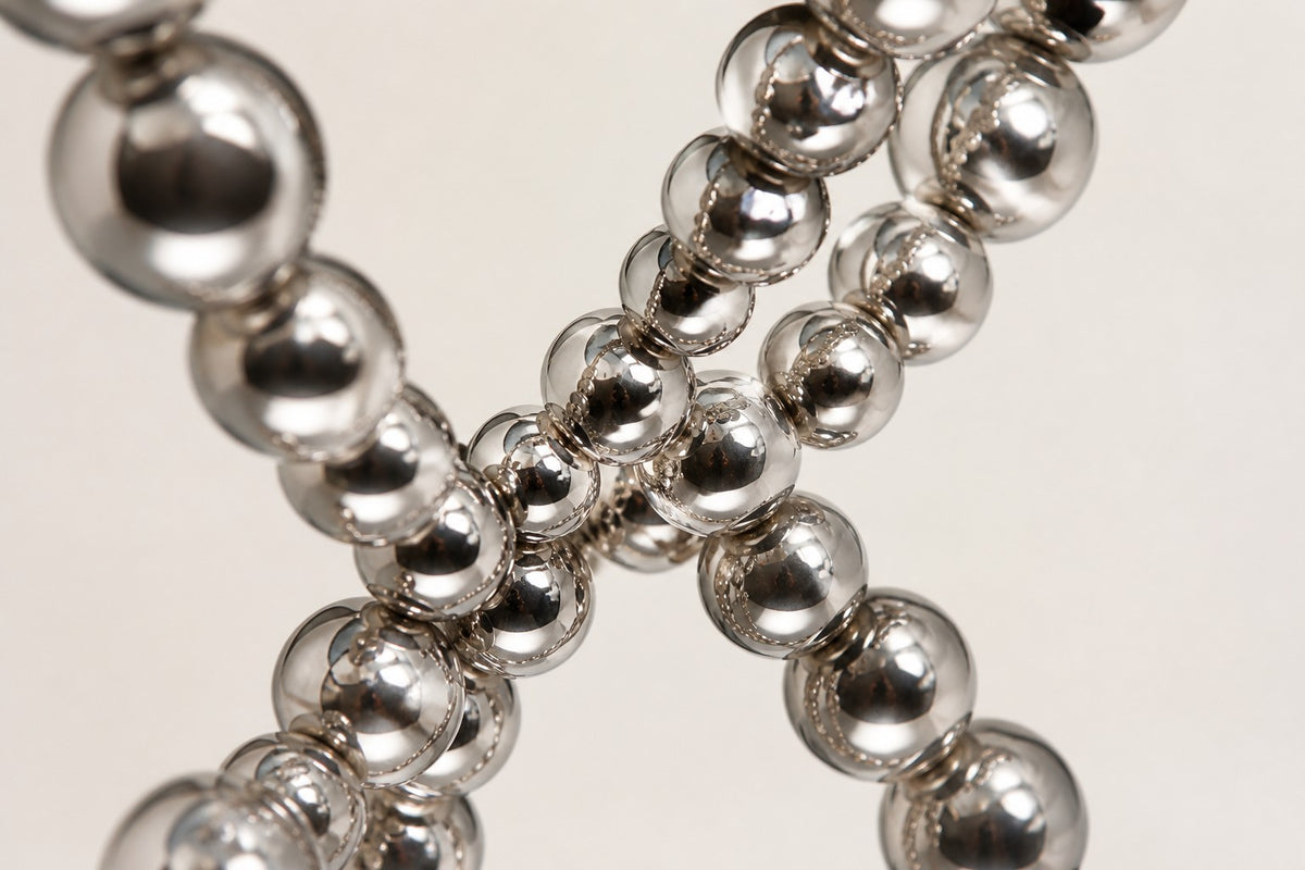 Thuraya — mirror chrome beaded figure-eight sculpture on a black base, close detail of the surface and edge