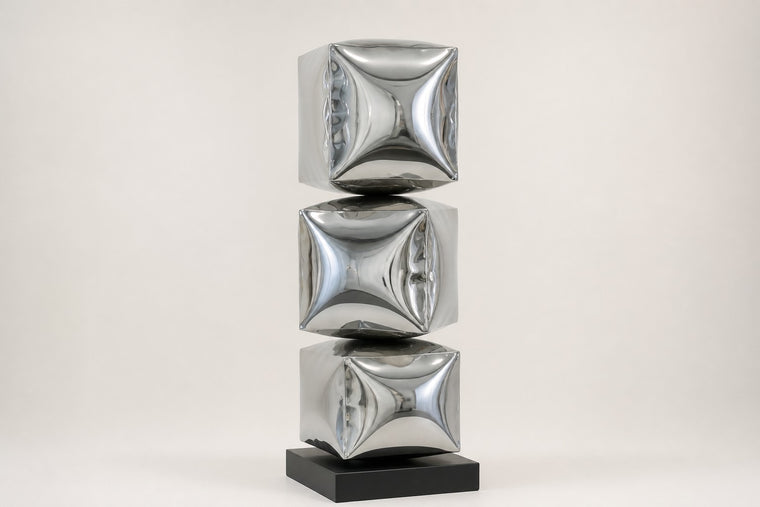 Tsumiki — 90 cm three stacked mirror-chrome inflated cubes on a black base, studio view of the whole piece