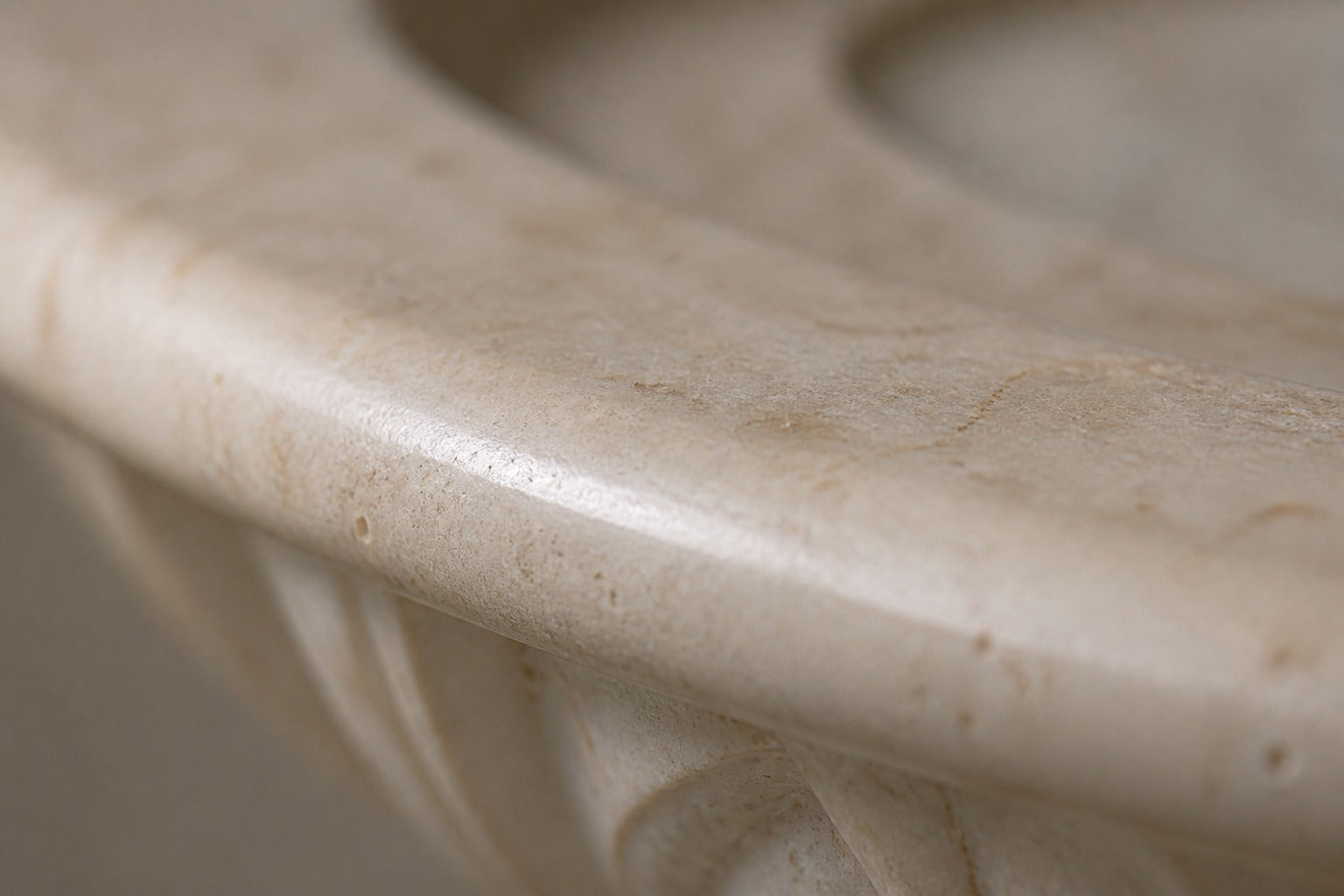 Pale limestone pedestal fountain Vasca Ø65, cream and white with amber veining, on a pale stone floor.
