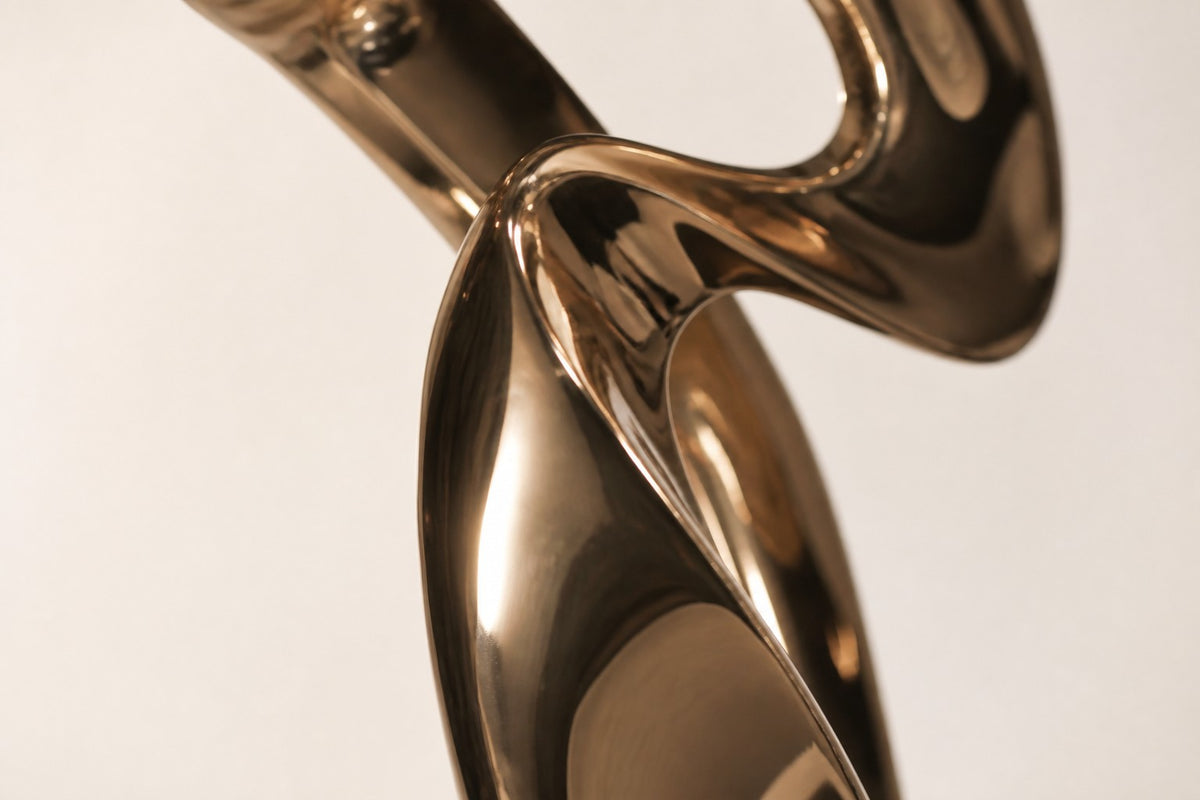 Vega — polished rose bronze abstract wing sculpture on a black base, close detail of the surface and edge