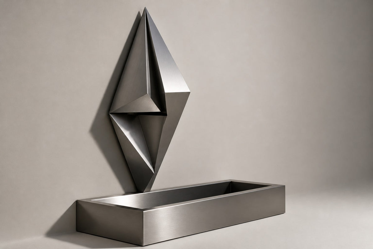 Veila — faceted stainless wall fountain, studio side angle showing its depth