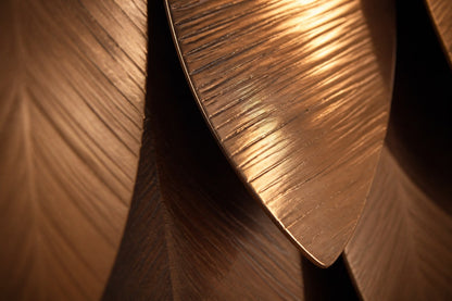 Wide panel of overlapping leaf forms in graded brown tones, leaning against a plaster wall.