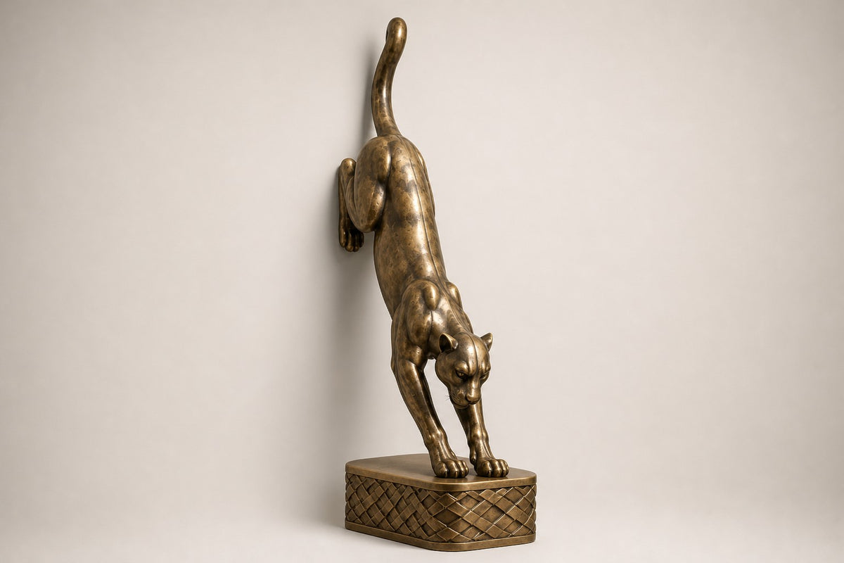 Wathba 150 — 150 cm antique brass wall sculpture of a panther stepping down onto a woven plinth, studio view of the whole piece