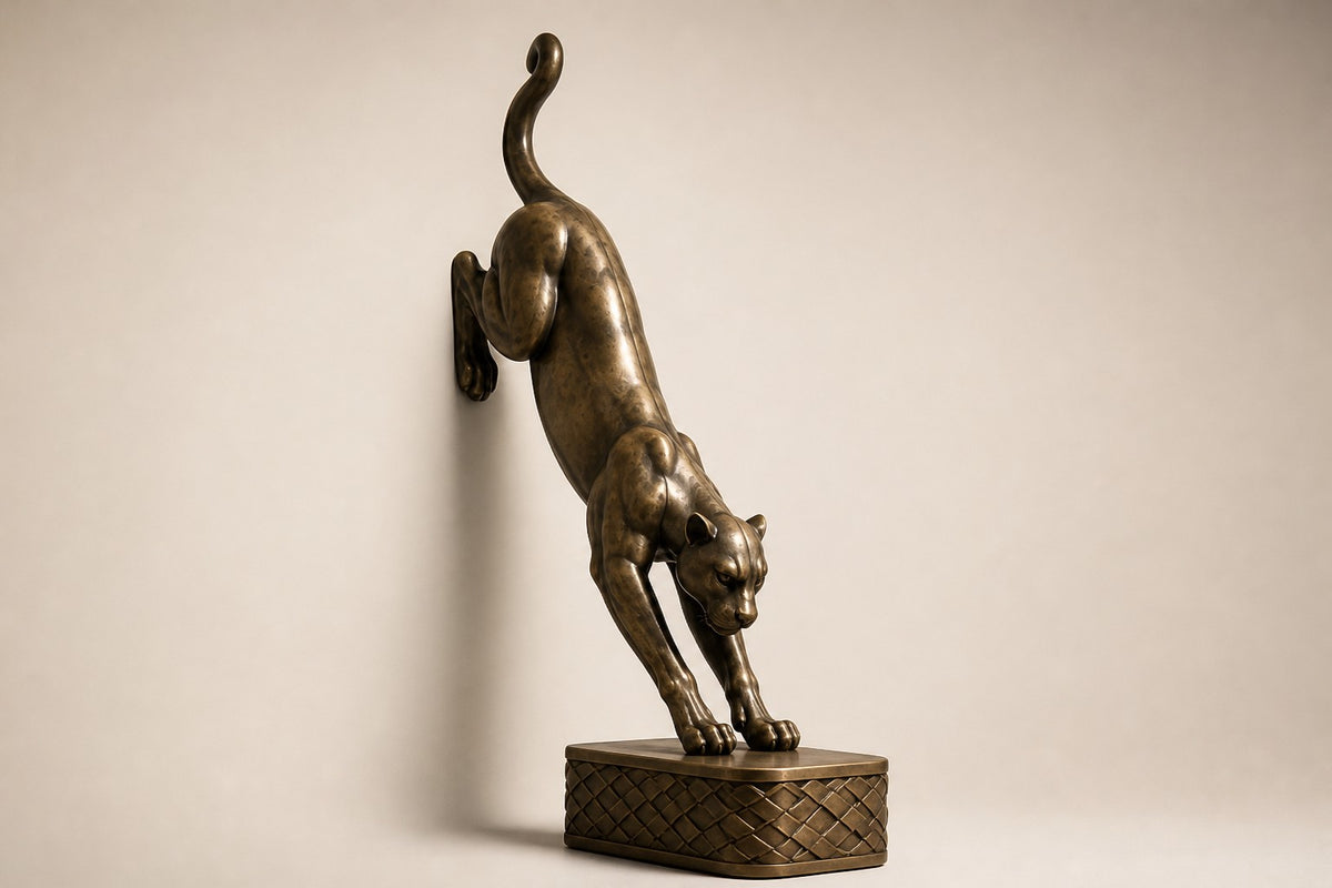 Wathba 150 — 150 cm antique brass wall sculpture of a panther stepping down onto a woven plinth, three-quarter studio view showing its profile