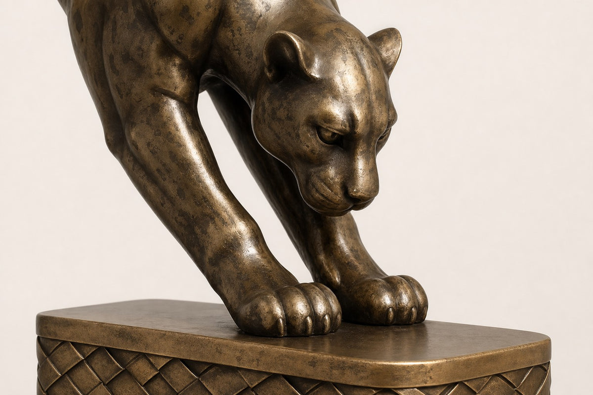 Wathba 150 — 150 cm antique brass wall sculpture of a panther stepping down onto a woven plinth, close studio detail of the surface and material