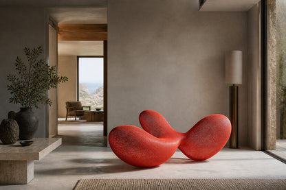 Coral red woven wire sculpture Zaurak, two full lobes drawn together through a narrow twist at the centre.